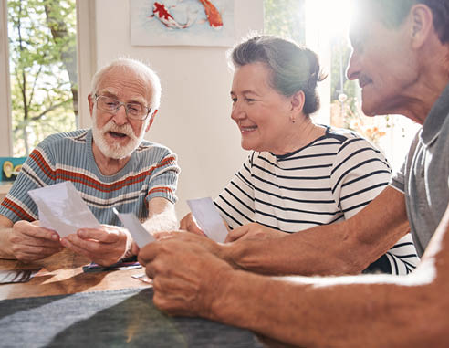 My memories. Three retirement people sitting at the table at the living room and watching at the old photos while spending their time at the nurse house